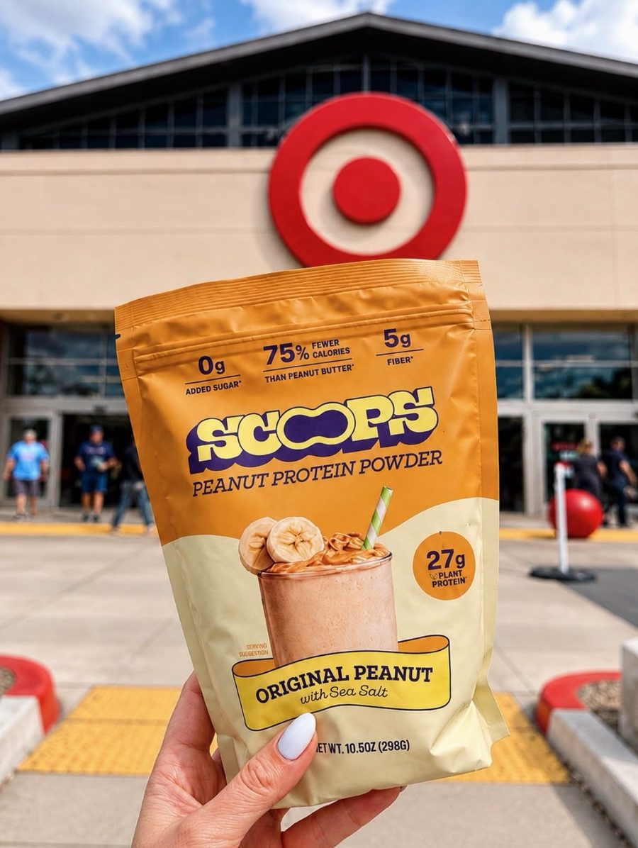 A hand holding a bag of Scoops Original Peanut protein powder outside a Target store